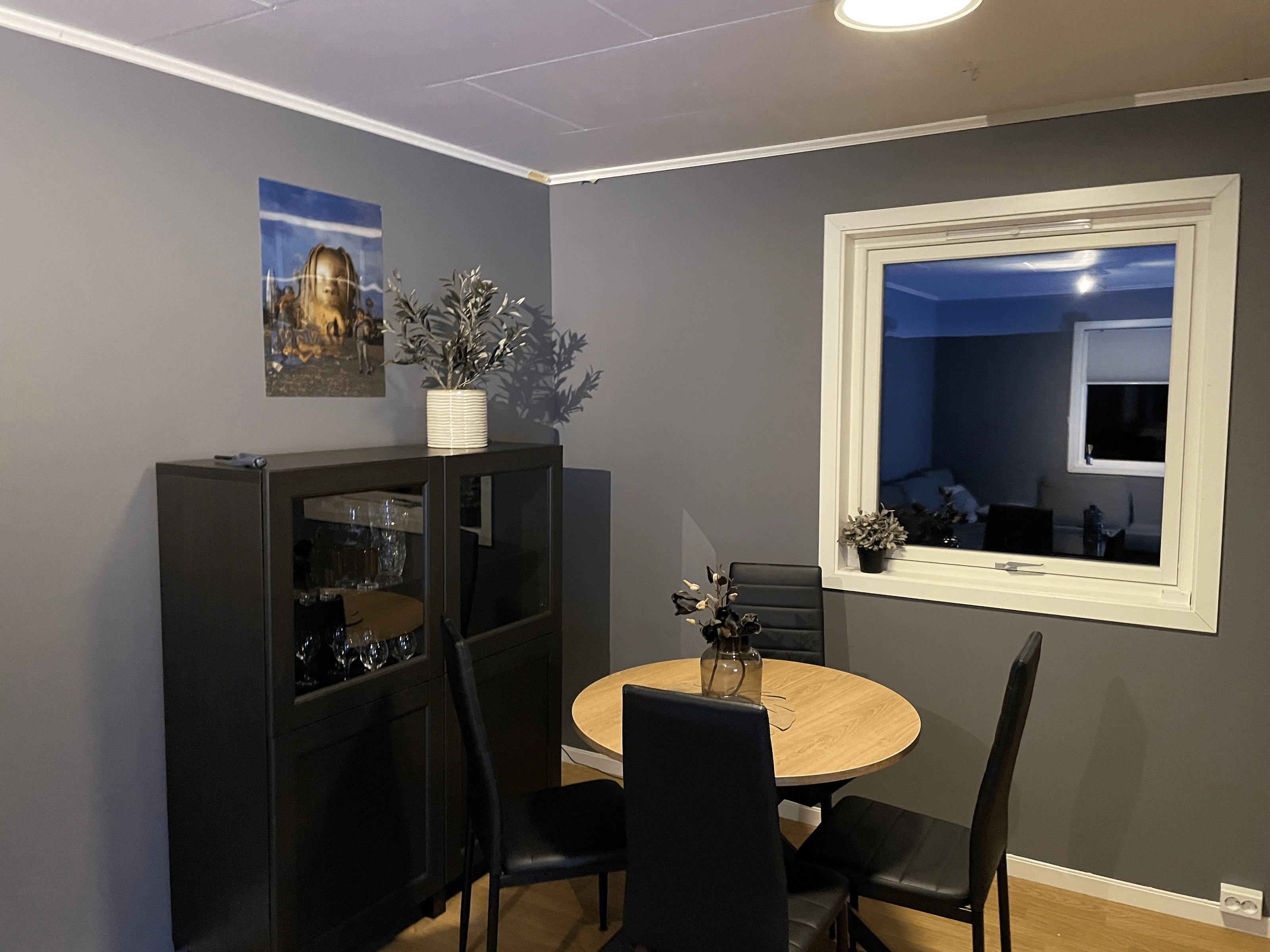 Dining nook with a round table and display cabinet in the renovated living room.